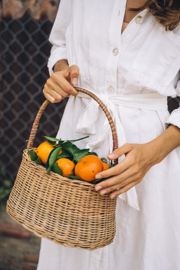 Mujer sosteniendo canasta con naranjas